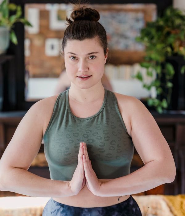 Woman holding a serene yoga pose in a dark room with cyan light.